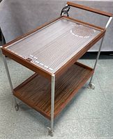 Three-quarter view of cart showing heating tray top, lower shelf and casters