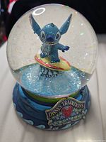 Front view of Stitch snow globe showing Disney Traditions plaque