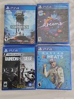 Four PS4 game cases arranged in grid: Star Wars Battlefront, Dreams, Rainbow Six Siege, NASCAR Heat 5