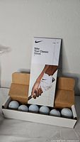 Nike Tour Classic glove box with open box of six Titleist golf balls