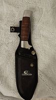 Knife in sheath displaying Mossy Oak logo and handle details