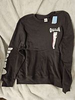 Full view of black Ouija sweatshirt front with tag attached