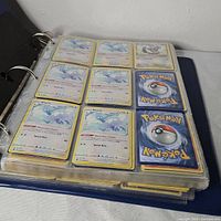 Binder open showing page with nine Altaria holographic cards and one Skwovet card