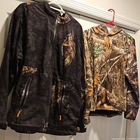 Both camouflage tops hanging on hangers