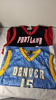 Both jerseys stacked, showing Portland lettering and Denver jersey front