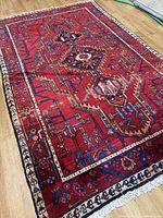 Full view of pink-red Hamadan rug on floor showing entire pattern and borders