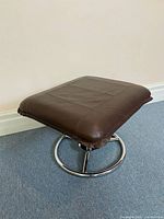 Overall view of ottoman showing chrome base and leather cushion
