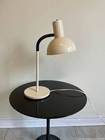 Full view of beige metal desk lamp on table