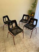 Four black resin stacking chairs overview