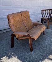 Front angled view of brown leather bentwood loveseat showing seat cushion wear and frame
