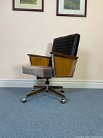 Side view showing walnut panels, velour seat, vinyl back, chrome base with casters