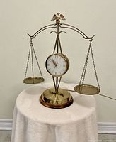 Full view of brass scales of justice electric clock on table