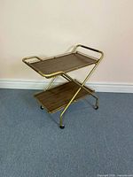 Angled view of bar cart showing top and lower shelves, brass frame, casters