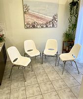 Front view of all four white resin stacking chairs with chrome legs