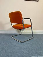Rear three-quarter view of orange Steelcase cantilever chair showing chrome frame