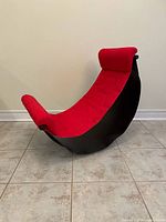 Full view of chair from front-left showing red seat cushion on black curved frame