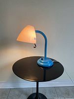 Full view of illuminated IKEA SMYG lamp showing blue base, gooseneck, white shade