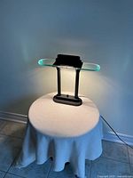 Front view of modernist lamp showing base, pillars, glass shelf and light housing