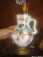 Front view showing ceramic jug body, brass base, hand-painted design