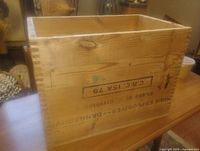 Front angled view of wooden crate showing stencilled text and dovetail joints