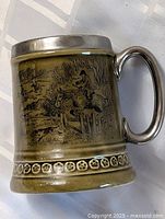 Full view of olive-green Wade tankard with hunting scene, metal rim and handle