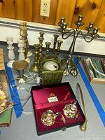 Overview of assorted candlesticks, candelabrum, ceramic lantern, silver-plated holders in case, brass accessories