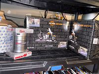 Shelf showing boxed Harley-Davidson telephone and keg-packaged Coors Light stock car