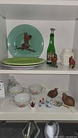 Shelf view showing Fiesta plates, 7UP bottle, cardinal figurine, Royal Doulton vase, ceramic quail, Noritake cups