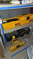 Shelf with five plastic toolboxes: two yellow, one black, one clear-lid organizer, another yellow