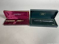 Both pens in their open boxes: Sheaffer gold-filled pen on left, Cross chrome pen on right