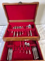 Open wooden chest showing full set of flatware in red felt interior