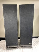 Front view of both speakers with grills and metal bases visible