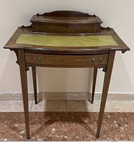 Front view of mahogany writing table showing leather top, drawer and legs
