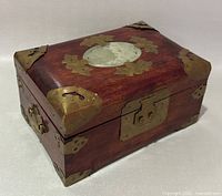 Closed jewelry box showing wood, brass mounts, jade medallion