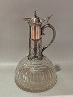 Full view of cut crystal claret jug with silver plated neck and handle