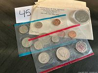 Full lot view with envelope, two coin packs, cased dollar and token