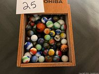 Top view of open wooden box filled with assorted glass marbles
