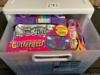 Drawer showing assorted toys including Glitterazzi pouch, markers, doll, sunglasses