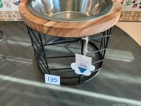 Full view of stainless bowl in wood rim on black metal stand with price tag