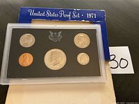 Front view of proof set showing five coins in holder within blue sleeve
