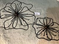Both metal flower wall hangings side by side on fabric surface