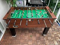Top angled view of full-size wood foosball table showing playing surface, rods, players, cup holders