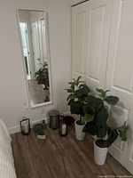 Mirror, faux plants, lanterns, trash can, soap set, wooden riser visible together