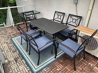 Overall view showing rectangular metal table, six chairs with blue cushions, rug