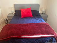 Front view of made queen bed showing headboard, bedding and pillows