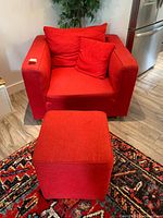 Red upholstered armchair with matching cube ottoman on patterned rug