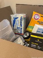 Box contents showing vacuum bags, flashlight, cleaning cloth, LED light packaging