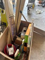 Box containing assorted supplies including packaged blind, vinyl wall base, wall plates, red bowl, misc hardware