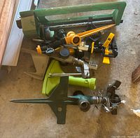 Pile of various lawn sprinklers on concrete