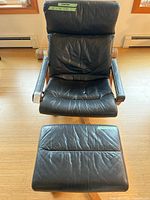 Front view of black leather swivel armchair and ottoman
